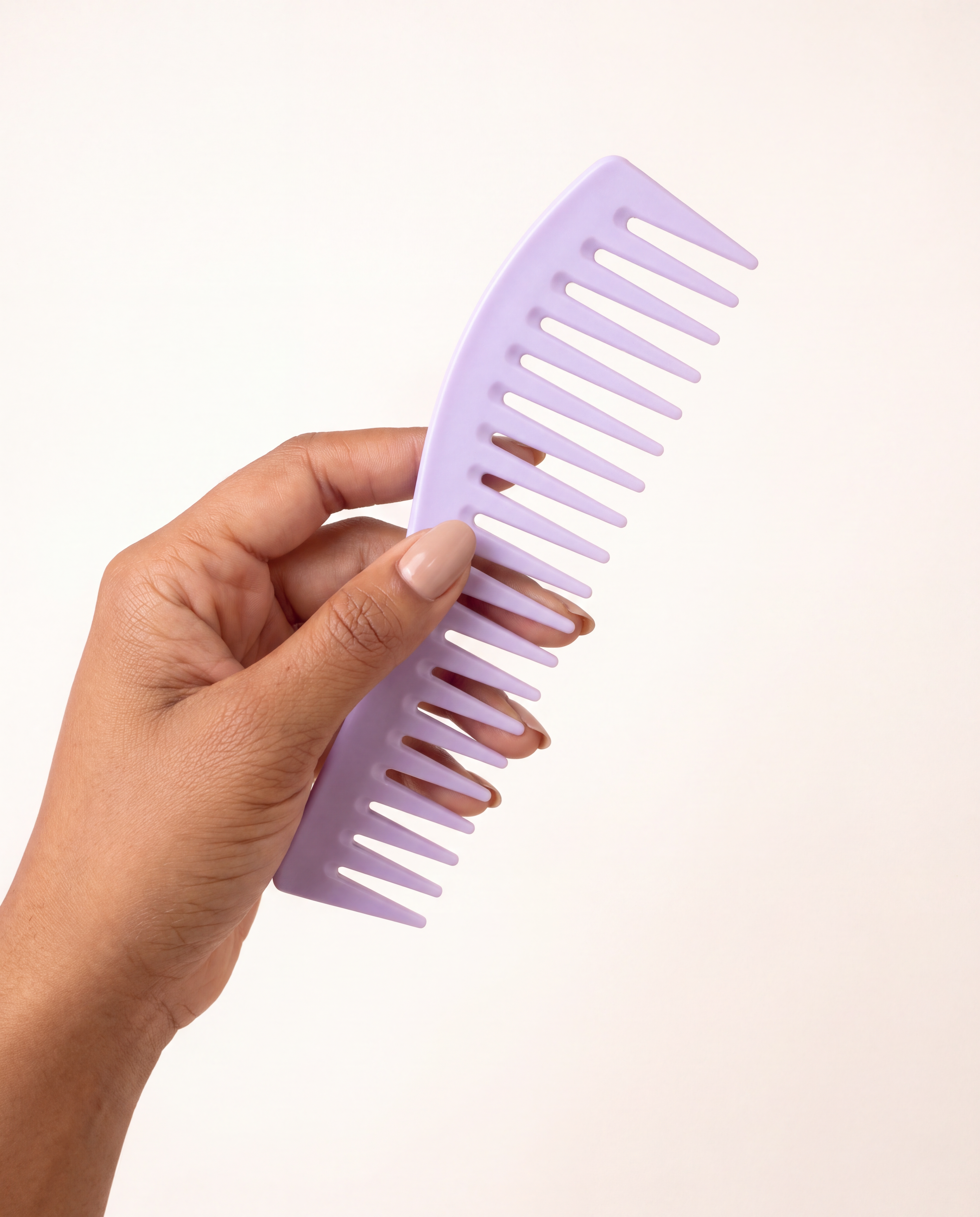 Hand holding the lavender wide-tooth detangling comb, showing its size and curved shape