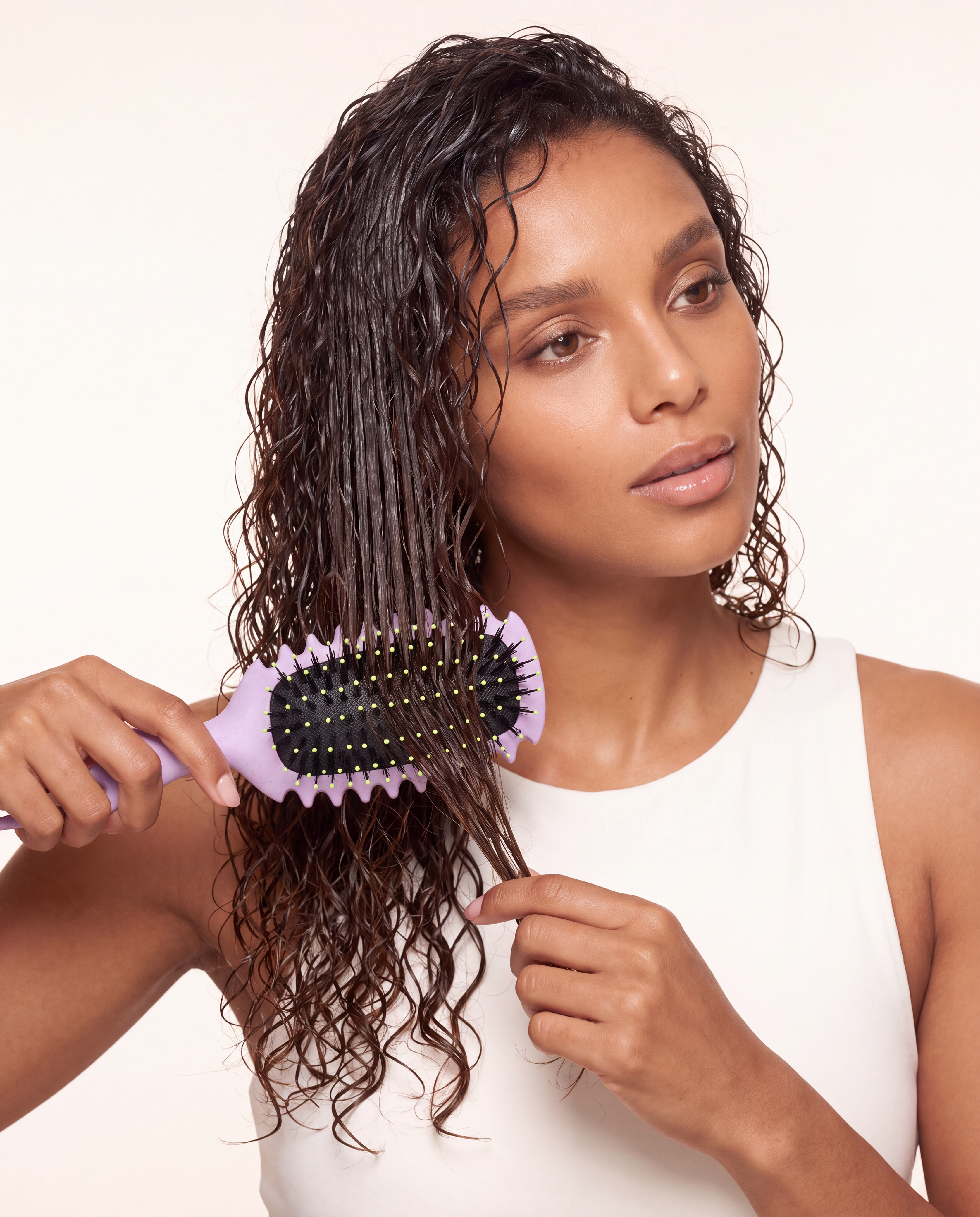 Woman using The Curl Trainer PRO curly hair brush to define wet curls on wash day