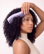Woman with curly hair using the lavender wide-tooth detangling comb at her crown